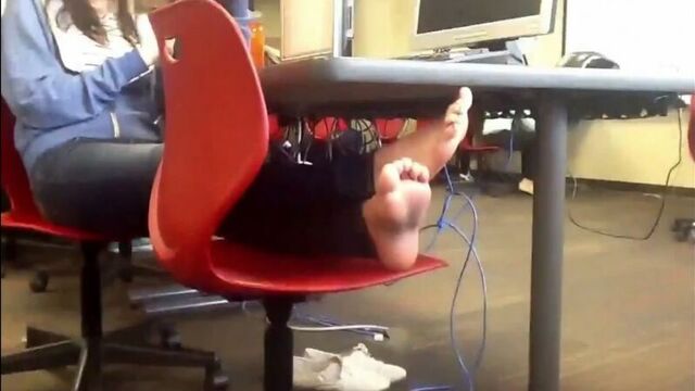 Девушка сидит в офисе с планшетом, положив ноги на стул